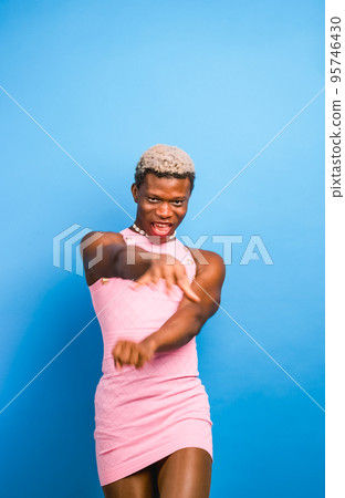 Black androgynous model in pink dress dancing 95746430