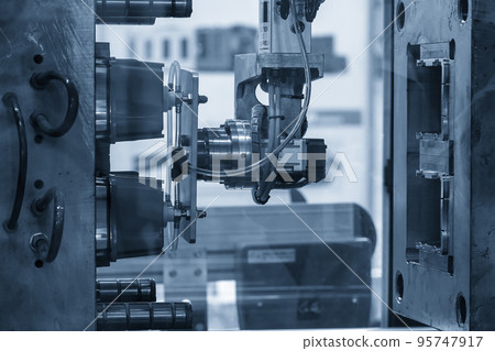 The robotic arm gripping the plastic cup from the injection machine. 95747917