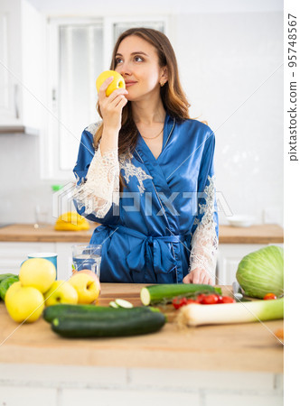 Portrait of positive woman eating apple at home 95748567