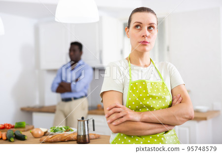 Upset young woman standing in kitchen after discord with husband 95748579