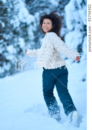 The woman having fun walking in snow covered winter forest The woman having fun walking in snow covered winter forest 95749302