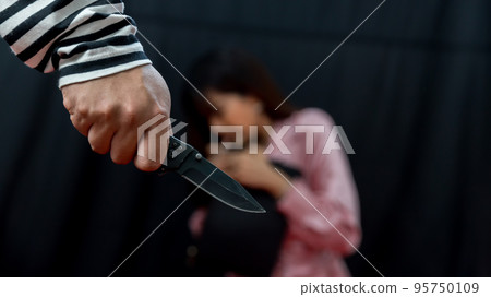 Thief is threatening woman. Robber is robbing woman by knife. Thief is threatening woman. Robber is robbing woman by knife. 95750109
