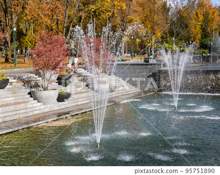 Fountains in Kharkiv city with red autumn trees Fountains in Kharkiv city with red autumn trees 95751890