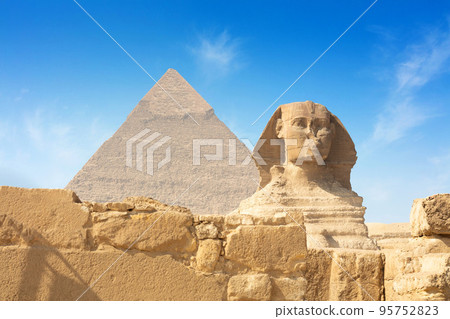Egyptian Great Sphinx full body portrait with head, feet with all pyramids of Menkaure, Khafre, Khufu in background on a clear, blue sky day in Giza, Egypt empty with nobody. 95752823