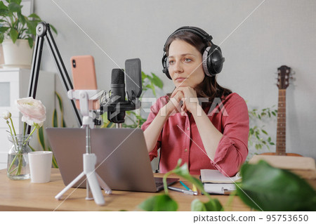 woman in a home office records podcast audio content with a microphone and headphones and a labrador dog woman in a home office records podcast audio content with a microphone and headphones and a labrador dog 95753650