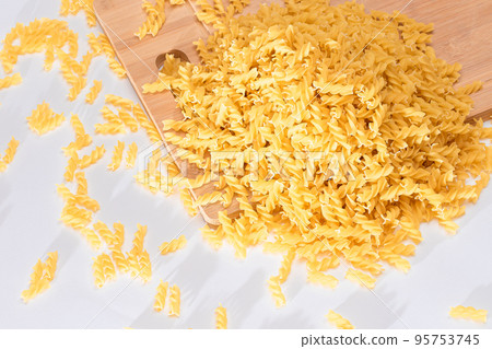 Uncooked Fusilli Pasta Scattered on Wooden Board Uncooked Fusilli Pasta Scattered on Wooden Board 95753745
