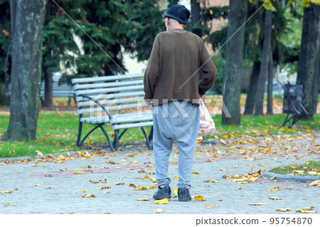 homeless poor man walks down the city street with a bag in his hand homeless poor man walks down the city street with a bag in his hand 95754870