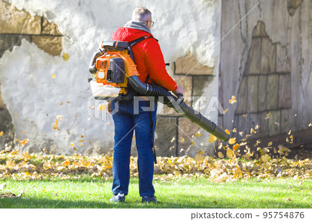 Leaf blower Male worker removes leaves lawn of garden autumn. Leaf blower Male worker removes leaves lawn of garden autumn. 95754876