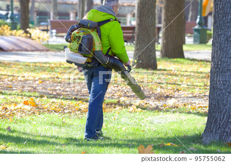 Working in the Park removes leaves with a blower. Park cleaning service Working in the Park removes leaves with a blower. Park cleaning service 95755062