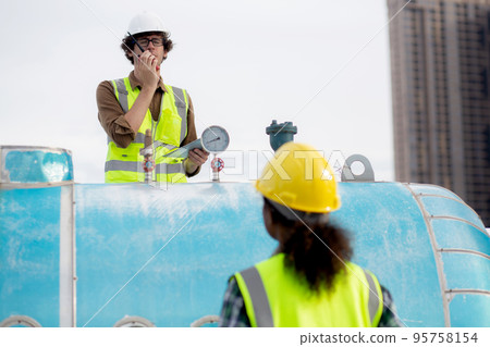 Young woman and man engineer check and examining pipeline and using radio in the factory. 95758154