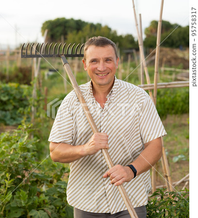 Portrait of man with working tool in backyard garden Portrait of man with working tool in backyard garden 95758317