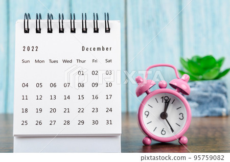 The December 2022 Monthly desk calendar for the organizer to plan 2022 year with pink alarm clock on wooden table. 95759082