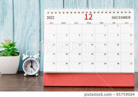 The December 2022 Monthly desk calendar for the organizer to plan 2022 year with alarm clock on wooden table. 95759084