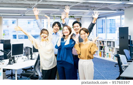 A smiling business group wearing office casual clothes to banzai 95760397