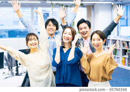 A smiling business group wearing office casual clothes to banzai 95760398