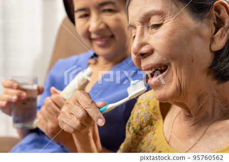 Caregiver take care asian elderly woman while brush teeth. 95760562