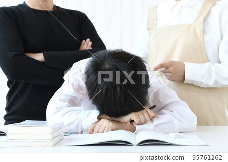 一個低著頭趴在桌子上的孩子和一個責罵的父母 95761262