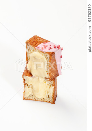 Cut in half cube shaped croissant with vanilla custard, berry icing and candied raspberry 95762380