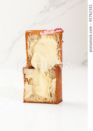 Sliced fluffy cube shaped croissant with vanilla custard filling, pink glaze and candied berries 95762381