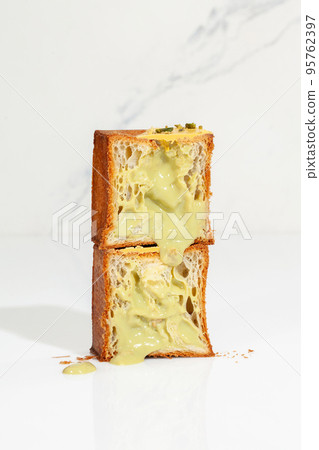 Two halves of flaky sweet cube croissant with pistachio custard and nut crumbs Two halves of flaky sweet cube croissant with pistachio custard and nut crumbs 95762397