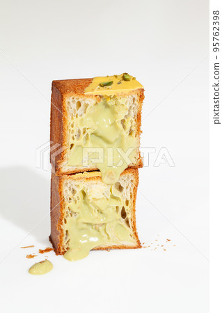 Cut in half fluffy cube shaped croissant with pistachio cream and nut crumbs Cut in half fluffy cube shaped croissant with pistachio cream and nut crumbs 95762398