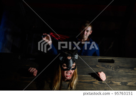 nipple tapes. A woman is imprisoned in a wooden pillory during sexual games. BDSM Erotic fantasies. Subordination. Toys for adults. The mask of the cat. The man in the shirt dominates. 95763151