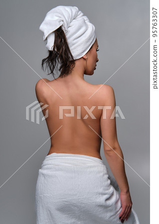Young beautiful brunette woman after shower with white towel on her head and hips 95763307