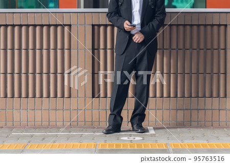 一個等待通勤列車的人玩智能手機的身影 一個等待通勤列車的人玩智能手機的身影 95763516