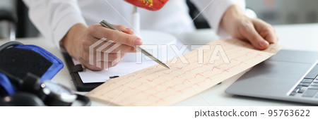 Doctor cardiologist examines electrocardiogram of patient heart in cardiology 95763622