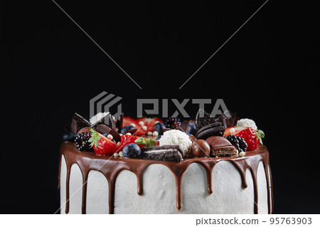 Birthday cake on dark background with copy space. Close up of cake decorated with fresh berries and chocolate sweets on dark background. Delicious dessert for party Birthday cake on dark background with copy space. Close up of cake decorated with fresh berries and chocolate sweets on dark background. Delicious dessert for party 95763903