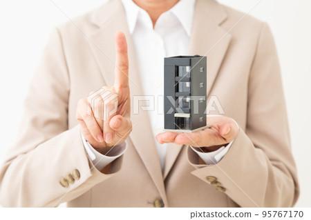 一位穿著西裝的中年婦女拿著公寓模型並舉起食指 95767170