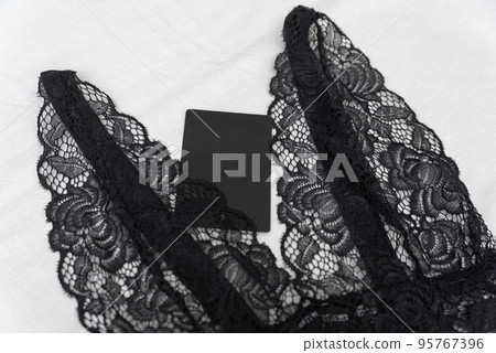 Black lace bralet with empty black tag on white background. Transparent lace sexy lingerie 95767396