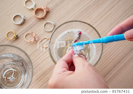 Jeweller hand cleaning and polishing vintage jewelry diamond ring closeup Jeweller hand cleaning and polishing vintage jewelry diamond ring closeup 95767431