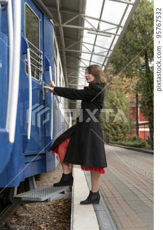 Full length portrait of young old-fashioned woman near train. Retro vintage 30-40s style. Vertical frame. Full length portrait of young old-fashioned woman near train. Retro vintage 30-40s style. Vertical frame. 95767532