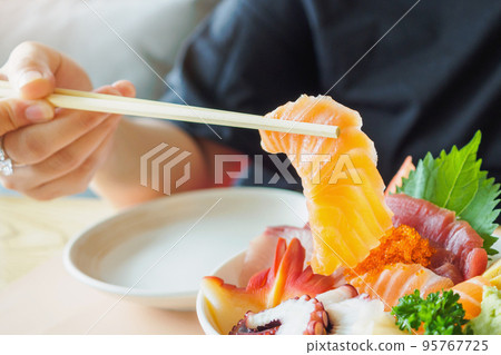 Salmon slice in chopsticks, Eating Sashimi Rice Bowl Chirashi Don Japanese food Salmon slice in chopsticks, Eating Sashimi Rice Bowl Chirashi Don Japanese food 95767725