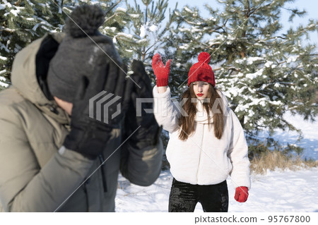 Young woman and boy are playing snowballs in winter forest. Friendship, relationships. Winter holidays 95767800