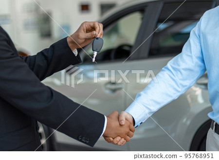 Close up of consultant giving car key to buyer after successful deal in auto show Close up of consultant giving car key to buyer after successful deal in auto show 95768951