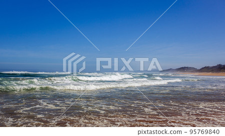 Sea beach with beautiful waves against bright blue summer sky. 95769840