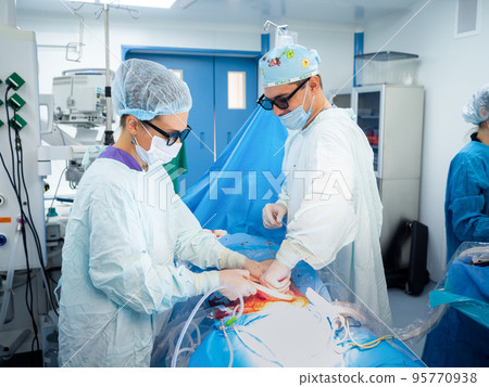 A team of doctors in 3D glasses operate on the patient's abdominal cavity.  95770938