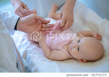 Surgeon checking babys legs for dysplasia Surgeon checking babys legs for dysplasia 95772173