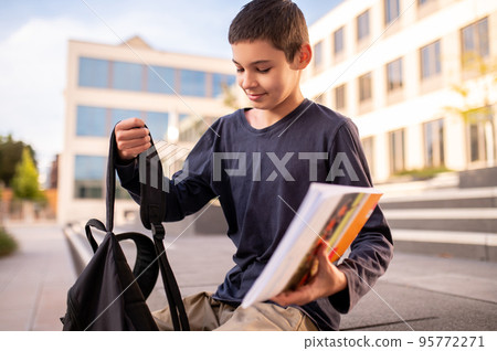 Schoolboy with a book and schoolbag outdoors 95772271