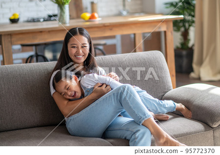 Cheerful mother entertaining her child at home Cheerful mother entertaining her child at home 95772370