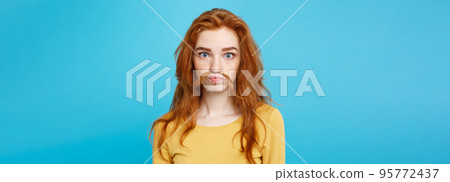 Headshot Portrait of happy ginger red hair girl imitating to be man with hair fake mustache. Pastel blue background. Copy Space. 95772437