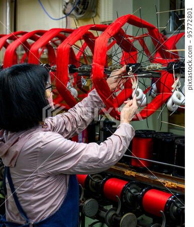 A woman winding up silk thread dyed red A woman winding up silk thread dyed red 95772801