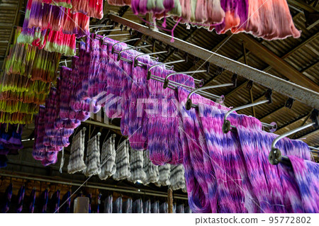 Conveyor transports textiles dyed in various colors for drying in the factory 95772802
