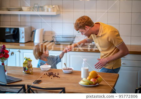 Young father and his cute little son getting ready for breakfast in the kitchen 95772806