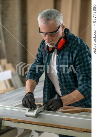Craft man in plaid shirt working in a carpenter workshop Craft man in plaid shirt working in a carpenter workshop 95772880