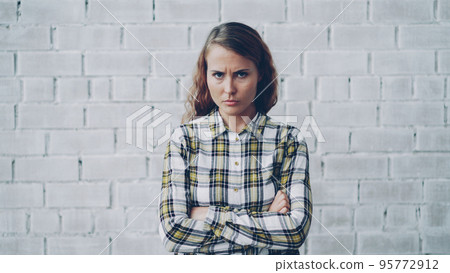 Portrait of angry young lady looking at camera, frowning and shaking her head expressing disappointment and disapproval standing with arms crossed and breathing heavily. Portrait of angry young lady looking at camera, frowning and shaking her head expressing disappointment and disapproval standing with arms crossed and breathing heavily. 95772912