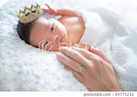 Newborn baby staring at daddy's hand 95773232