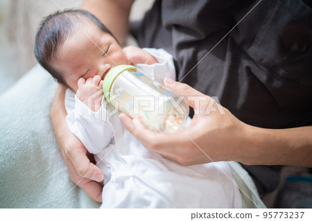 剛出生的嬰兒被爸爸抱著喝牛奶 95773237